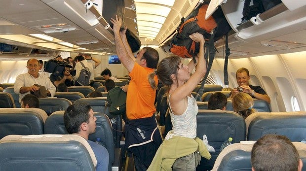 Varios turistas colocando su equipaje de mano